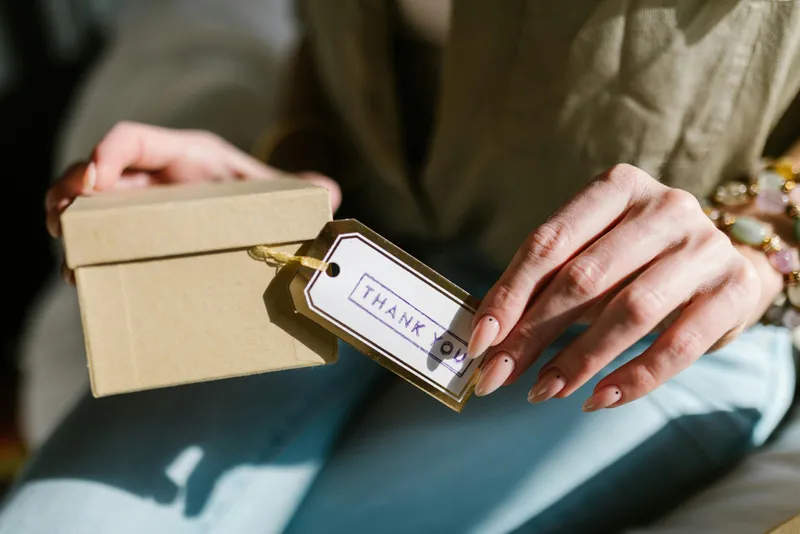 A person holding a FernWell Wellness Box filled with teas, candles, and natural remedies, symbolizing holistic self-care and everyday wellness rituals.