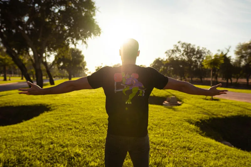 Person standing in a park with arms open, symbolizing holistic wellness and balanced living at Vita Integrative.